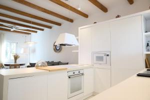 a white kitchen with white cabinets and a table at Senza's Cycladic Home in Marpissa , Paros in Kampos Paros +14 photos