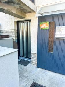 a garage with a blue door with a sign on it at Aloé Apartman Sopron in Sopron +4 photos