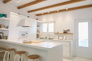 a white kitchen with a counter and stools at Senza's Cycladic Home in Marpissa , Paros in Kampos Paros