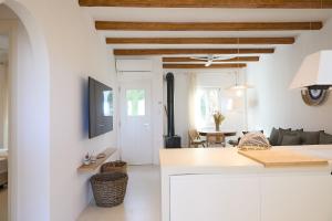 a kitchen and living room with white walls and wooden ceilings at Senza's Cycladic Home in Marpissa , Paros in Kampos Paros