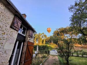 a hot air balloon in the sky over a house at Le chant des bois - à 5 min du Château de Chenonceau in Chisseaux
