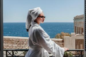 a woman standing on a balcony looking out at the ocean at The Hub Syros in Ermoupoli