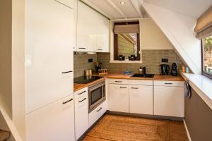 a kitchen with white cabinets and a window at Boshuisje Rekem - Ember in Lanaken