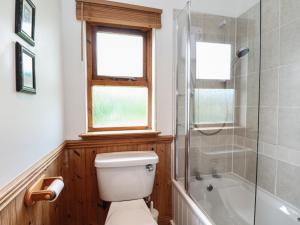 a bathroom with a toilet and a shower and a window at Creag Mhor Lodge in Arisaig +32 photos