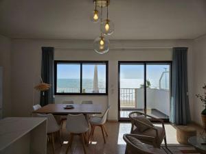 un salon avec une table et des chaises et l'océan dans l'établissement Apartamento moderno na praia com varanda grande, à Quarteira