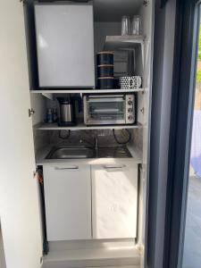 a kitchen with white cabinets and a refrigerator at Contemporary garden studio in Brighton! in Brighton & Hove