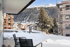 a balcony with two chairs in the snow at Modern Alpine Stay Terrace Central Davos in Davos