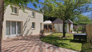 a house with a brick driveway in the yard at Les Trois Palmiers - Jardin, Jacuzzi privatifs in Les Bréviaires