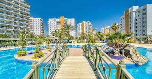 a bridge over a swimming pool with buildings in the background at Marcellus Iskele Resort Ceasar in Larnaca