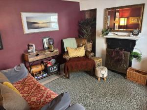 a living room with a couch and a chair and a fireplace at Loch Ness village cottage for 2 with free parking & pets welcome in Drumnadrochit