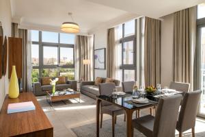 un soggiorno con tavolo, sedie e divano di Marriott Executive Apartments Doha, Le Mirage City Walk a Doha
