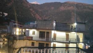 a large white building with a mountain in the background at Sandeep homestay in Dharamshala
