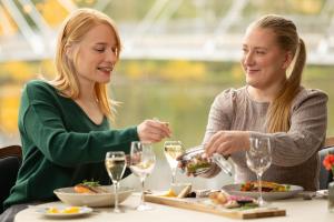 two women sitting at a table eating food and drinking wine at Finlandia Hotel Alba in Jyväskylä +130 photos