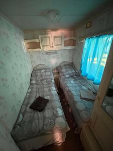 two beds in a small room with blue curtains at Domki Olia in Choczewo