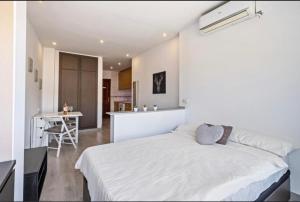 ein Schlafzimmer mit einem weißen Bett und einer Küche in der Unterkunft Cala de Mijas Beach & Golf Studio in La Cala de Mijas
