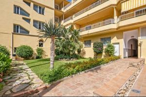 ein Apartmenthaus mit einem Innenhof mit einer Palme in der Unterkunft Cala de Mijas Beach & Golf Studio in La Cala de Mijas