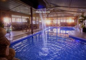 a large pool with a waterfall in a hotel room at Village Praia do Rosa in Praia do Rosa