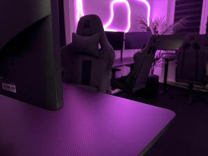 uma sala com luzes roxas e um monitor de computador em World of Esport em Bayreuth mais 1 fotografia