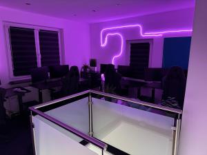a purple room with a table and chairs with a neon sign at World of Esport in Bayreuth