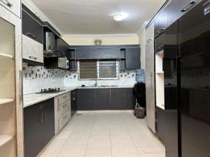 a kitchen with black cabinets and a white tile floor at Premium, Cozy And Budget friendly in Karachi +12 photos