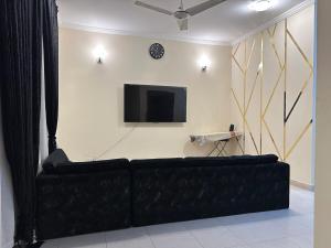 a living room with a black couch and a tv at Premium, Cozy And Budget friendly in Karachi