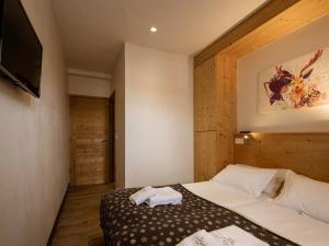 Un dormitorio con una cama y un televisor de pantalla plana. en Appartement 4 pièces pour 6 personnes, 4*, exposition Sud-Ouest, Valloire, proche télécabine et commerces - FR-1-263-362, en Valloire