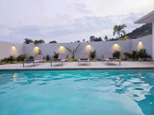 a swimming pool with chairs next to a white wall at Private villa near beach Koh Samui in Koh Samui