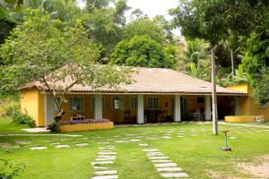 a yellow house with a yard in front of it at Vila Iriri - Pousada e Camping in Anchieta
