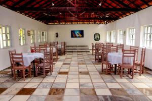 a restaurant with tables and chairs in a room at Vila Iriri - Pousada e Camping in Anchieta