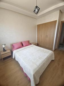a bedroom with a large white bed with pink pillows at Studio Zen vue sur mer in Aïn Harrouda +25 photos
