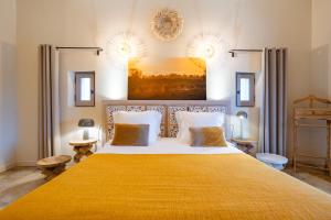 a bedroom with a large bed with a yellow blanket at Mas du Couvin, maison d'hôtes en Camargue in Saintes-Maries-de-la-Mer