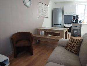 a living room with a table and a chair and a kitchen at Petite maison de ville dans un quartier calme in Bourbourg