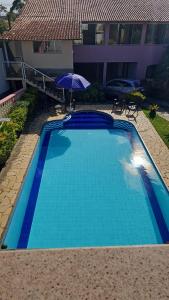 a blue swimming pool with an umbrella next to a building at Suíte Aconchego 4 in Miguel Pereira