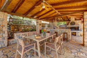 a patio with a table and chairs and a fireplace at Mariza Luxury Villa With Pool by goutos properties in Porto Heli