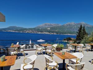 a patio with tables and chairs and a view of the water at Agape Rose Hotel in Tivat