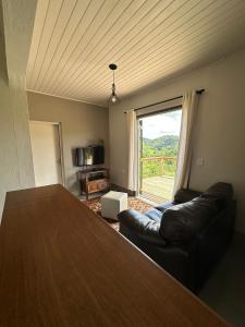- un salon avec une table, un canapé et une fenêtre dans l'établissement Chalé Serra do Luar, à Santo Antônio do Pinhal 29 autres photos