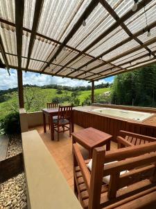 un patio avec une table et des chaises et un bain à remous dans l'établissement Chalé Serra do Luar, à Santo Antônio do Pinhal