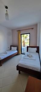 two beds in a room with a window at 2 Palmat Hotel in Ksamil