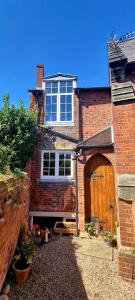a brick house with a wooden door and a building at Cosy Cottage in Melbourne in Melbourne