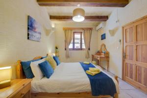 a bedroom with a large bed with blue pillows at Haven Farmhouse with Private Pool and Sea Views in Għajn Melel +45 photos
