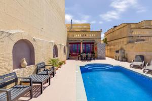 a swimming pool with benches next to a building at Haven Farmhouse with Private Pool and Sea Views in Għajn Melel