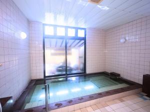 a swimming pool in a bathroom with a window at Oyado Hachibei in Takayama