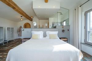 a bedroom with a large white bed with white pillows at Mas du Couvin, maison d'hôtes en Camargue in Saintes-Maries-de-la-Mer