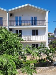 ein weißes Haus mit blauen Fenstern und Bäumen in der Unterkunft N&M apartments in Vodice