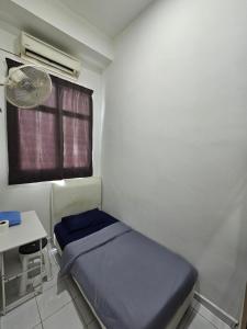 a small room with a bed and a fan at Sunny Point Hostel in Gelugor