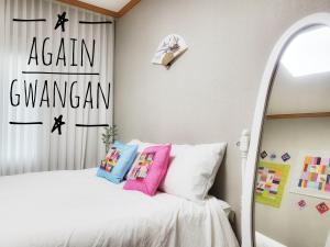 una camera da letto con un letto bianco e uno specchio di Again Gwangan a Busan