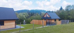 a small wooden house in a field with a fence at Domki na Stodoliskach in Kasinka Mala +12 photos