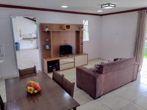 a living room with a table and a couch and a television at Casa do Sossego na Praia Guarajuba Barra do Jacuipe in Camaçari