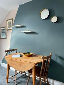 einem Esstisch mit 2 Stühlen und einer blauen Wand in der Unterkunft Cosy Loft Apartment with Sea Views Above Village Pub The Stag Inn Crosby Maryport in Crosby + 6 Fotos