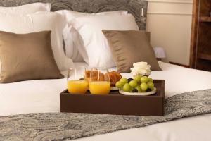 a tray of fruit and juice on a bed at Hotel Palais Bourbon in Paris